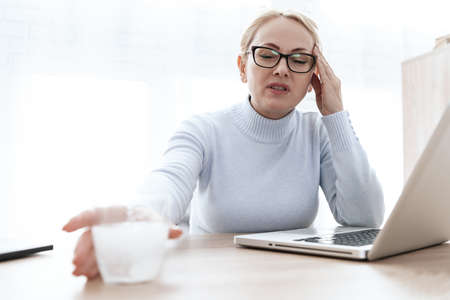 Woman sits and holds a glass with a tablet in handの写真素材