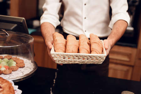 Young baker holds fresh pastries in his hands.の写真素材