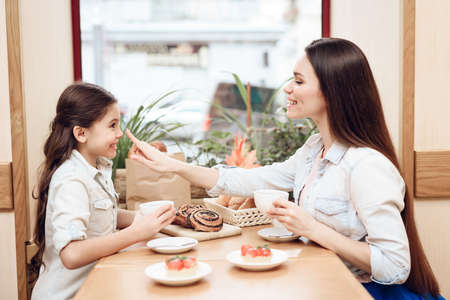 Mother with Daughter Eating Cakes in Cafeteria.の写真素材