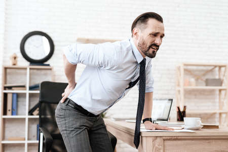 Man got up from chair and grabbed for a sore back.の写真素材