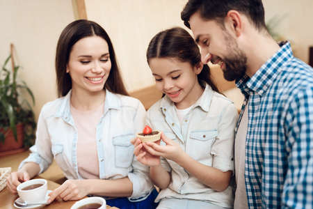 Young Happy Family Eating Cakes in Cafeteria.の写真素材