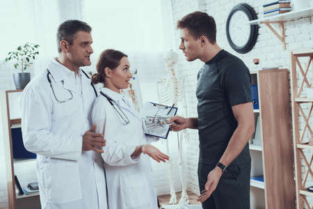 Male athlete bribes two doctors in the office.の写真素材