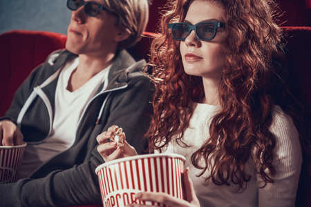 A woman sits with popcorn in her hands.の写真素材