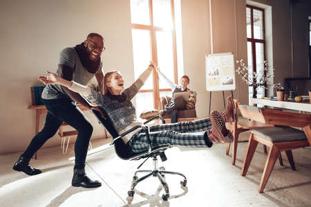 Cheerful colleagues having fun in office on chair.の写真素材