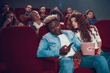 A man closes phone to his girlfriend at cinema.の写真素材