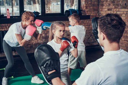 Little girl in gloves practicing blow with dad.