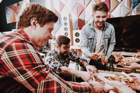 Man cuts off a piece of pizza and smiles.の写真素材