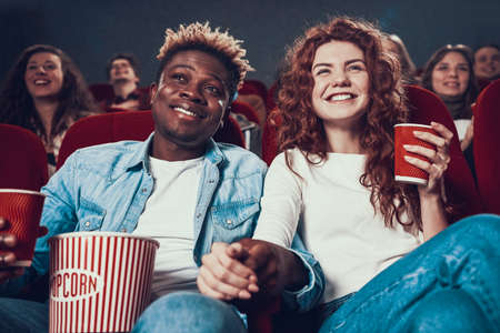 Young couple sitting in cinema and holding hands.の写真素材