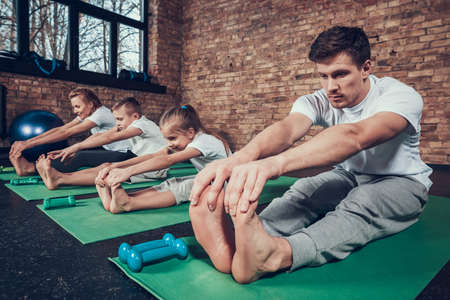 Family sitting on green mats in the gym.の写真素材