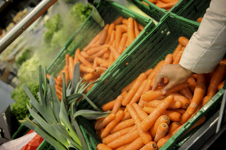 Woman buys carrot and food in the supermarketの写真素材