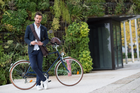 Businessman talking on cell phone sitting on his bicycle in cityの写真素材