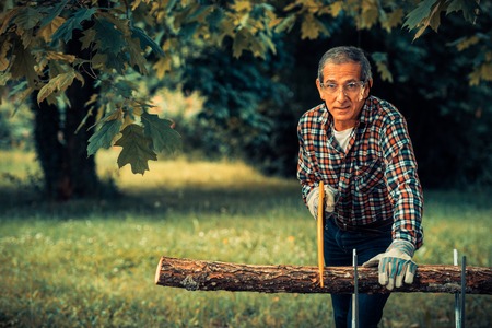 Senior man sawing a log handsaw closeupの写真素材