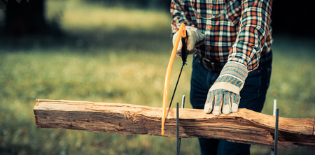 Senior man sawing a log handsaw closeupの写真素材