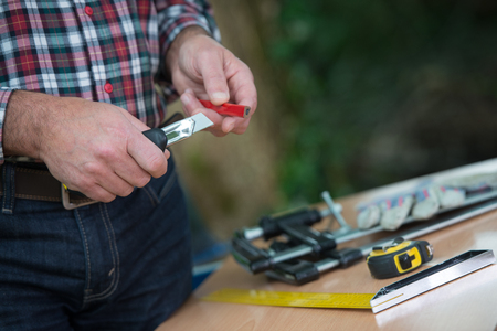 Sharpening of a carpenter's pencil with a blade knife outdoorの写真素材