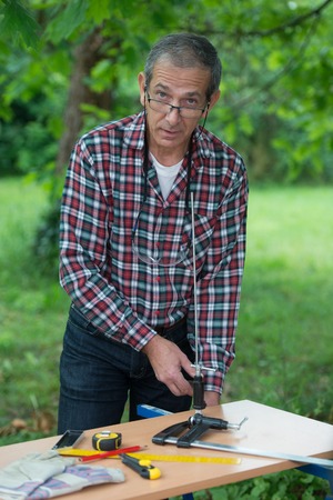 Senior Man screwing on a bench a tight seal outdoor
