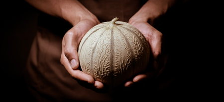 Melon in hand, Brown apron, close upの写真素材