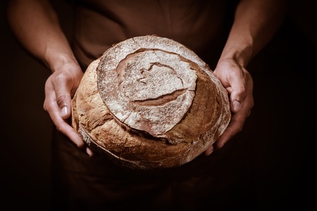 Baker man holding a beautiful round breadの写真素材