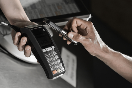 Payment in a trade with nfc system with mobile phone in supermarket.の写真素材