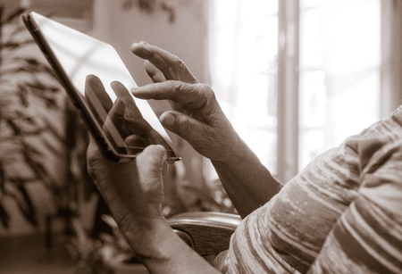 Hands of a senior woman using a tablet at homeの写真素材