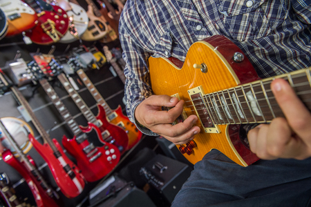 Young man playing the guitar in a shopの写真素材