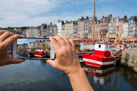 Smartphone in hand photographing, Honfleur harbour, normandy city in France Europeの写真素材