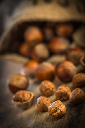 Hazelnut with peeled hazelnuts in jute bag on wooden background, Franceの写真素材