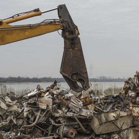 Large tracked excavator working a steel pile at a metal recycle yard, Franceの写真素材