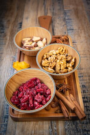 Mixed nuts and dried fruits in wooden bowl on wood background, copy spaceの写真素材