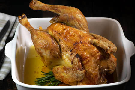 Roast chicken on a white plate, on a black wooden backgroundの写真素材