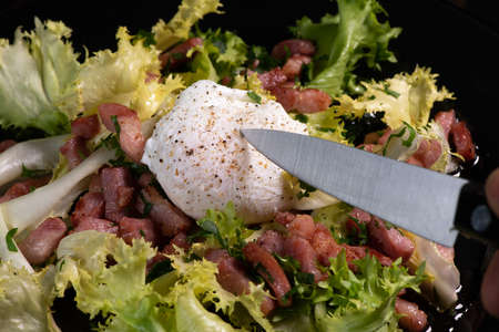 Recipe for poached egg cut with a knife, bacon and saladの写真素材