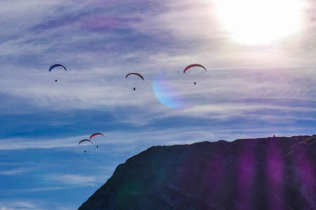 Paraglider flying over mountains in summer day in front of the mountain