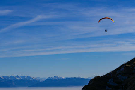 Paraglider flying over mountains in summer day in front of the mountainの写真素材
