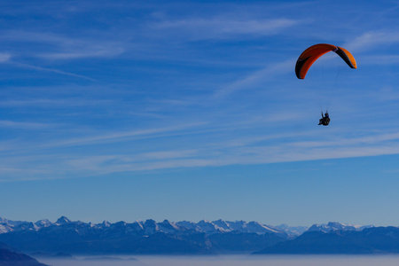 Paraglider flying over mountains in summer day in front of the mountainの写真素材