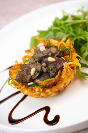 Recipe for poultry giblets in a nest of fried potatoes with rocket and tomato saladの写真素材