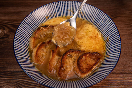 Classic French onion soup baked with cheese croutons sprinkled with fresh thyme, close up view.の写真素材