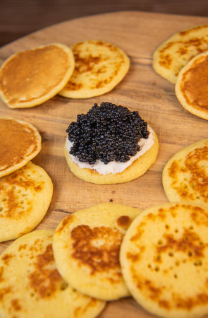 Blinis with black caviar and cream cheese, on a festive dish, mini pancakes, an elegant appetizerの写真素材