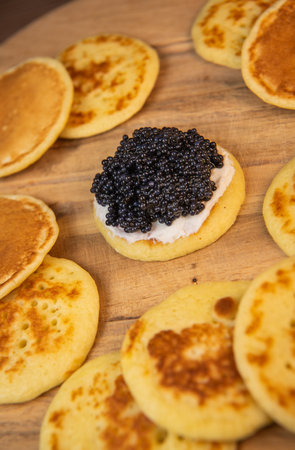 Blinis with black caviar and cream cheese, on a festive dish, mini pancakes, an elegant appetizerの写真素材