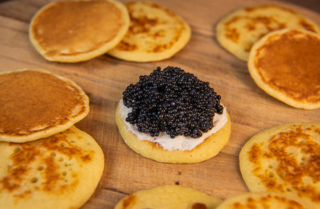 Blinis with black caviar and cream cheese, on a festive dish, mini pancakes, an elegant appetizerの写真素材