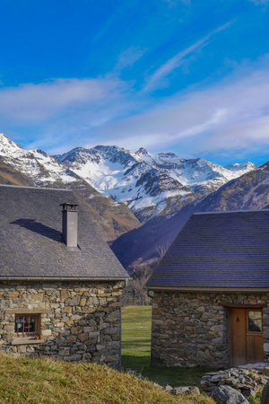 Stone cottages provide charming retreat against snowy mountain backdrop in peaceful valley