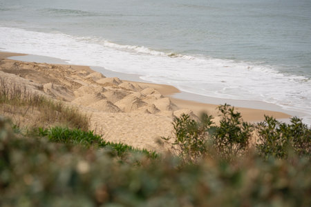Coastal landscape of Biscarrosse showcasing sand dunes and gentle waves along the shoreline in a...