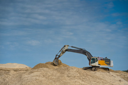 Coastline construction activity involves heavy machinery moving sand on a sunny day for erosion prevention at a coastal siteの写真素材