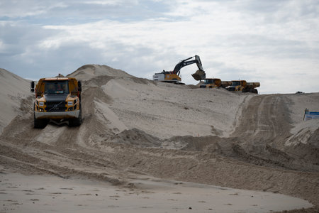 Construction activities reshaping the sand dunes at Biscarosse beach on the Atlantic Ocean in France during overcast weatherの写真素材