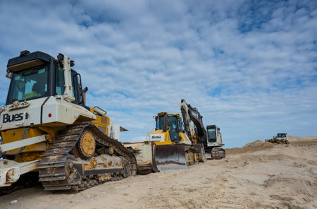 Construction equipment working along the coastline to manage erosion and prevent environmental...