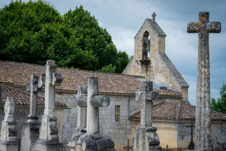 Stone cross cemetery near the church in Saint-Laurent-des-Combes highlighting religious heritage and historical architectureの写真素材