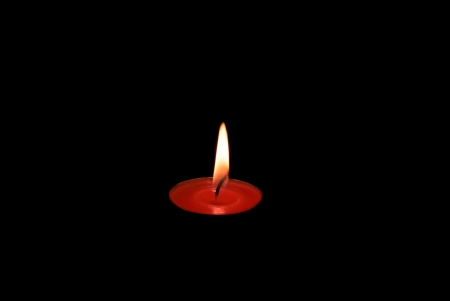 red candle burning in a dark spaceの写真素材