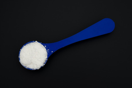powdered milk in a blue spoon on blackの写真素材