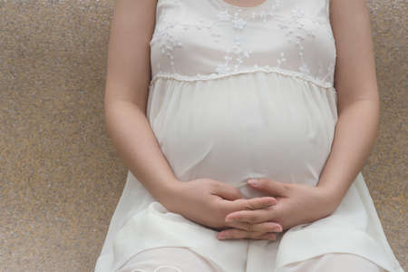 pregnant woman putting hands on bellyの写真素材