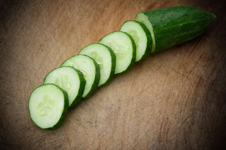 fresh cucumber slices on a wooden chop boardの写真素材