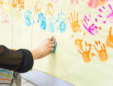 mother helps her young kid to make a hand printの写真素材