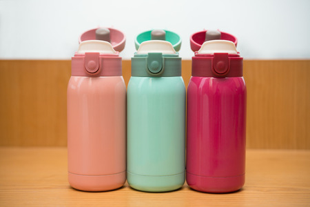 colorful thermal bottles on a wooden tableの写真素材